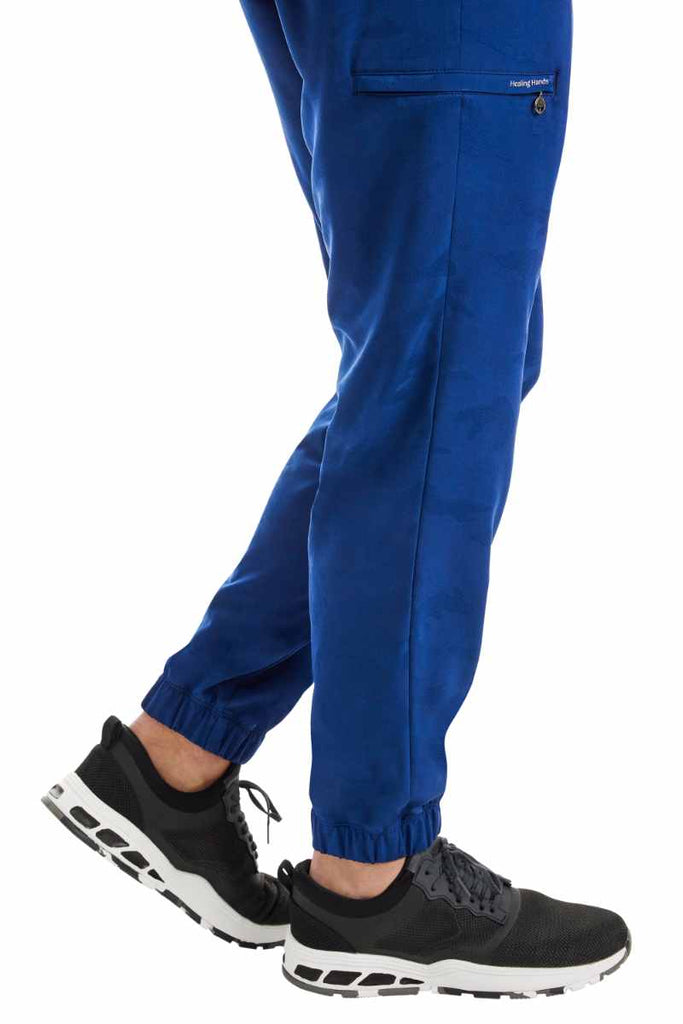 A young male Physical Therapist Aide wearing a Purple Label by Healing Hands Men's Drew Camo Jogger in Navy size XL featuring elastic cuffs at the leg opening.