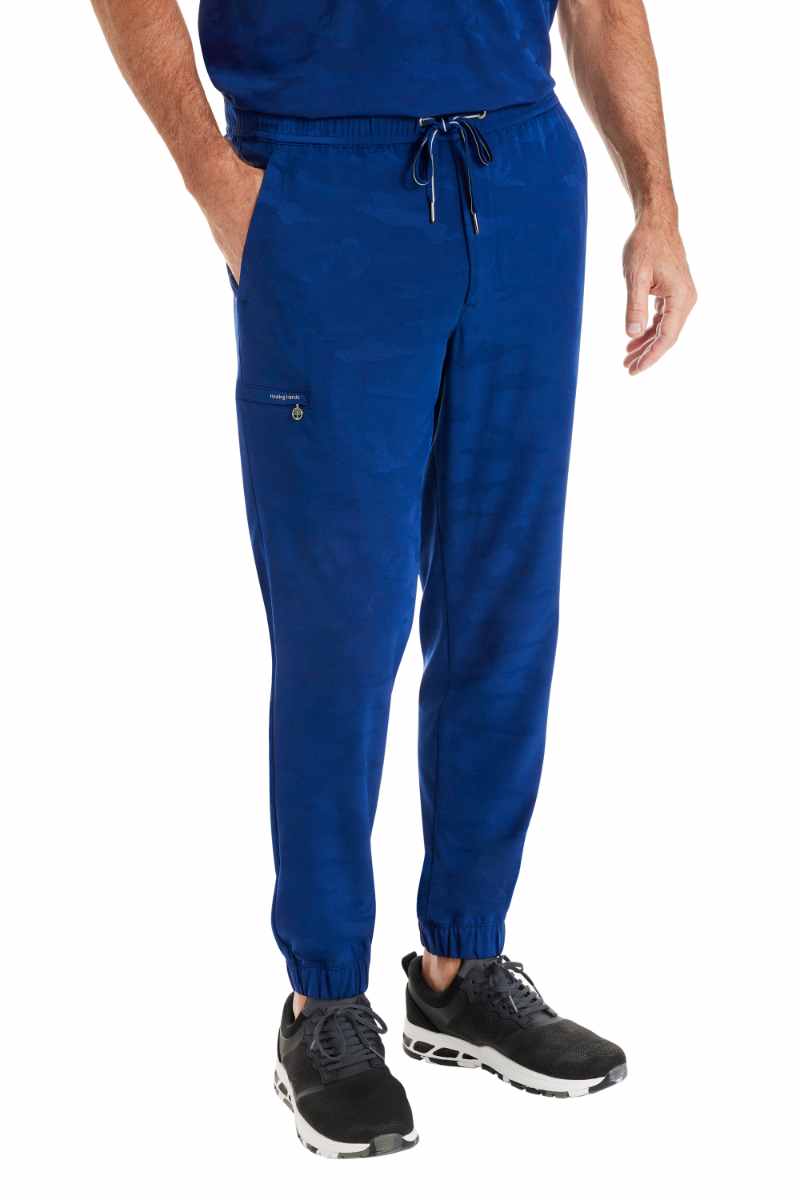 A young male Physical Therapist wearing a pair of Purple Label by Healing Hands Men's Drew Camo Jogger in Navy size Small featuring a total of 6 pockets.