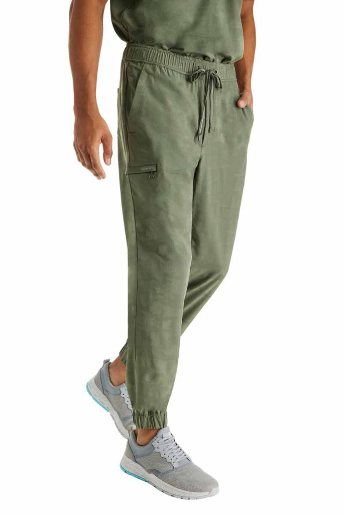 A young male Radiologic Technologist wearing a Purple Label by Healing Hands Men's Drew Camo Jogger in Olive size Medium featuring an elastic back & flat front.