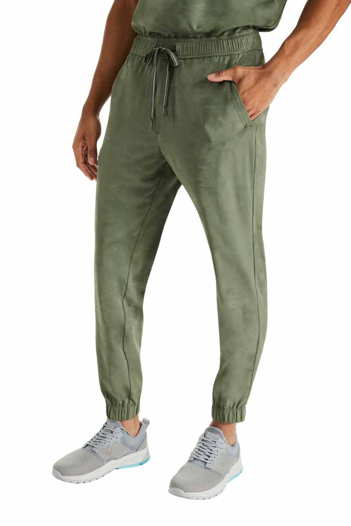 A young male Physical Therapist wearing a pair of Purple Label by Healing Hands Men's Drew Camo Jogger in Olive size Small featuring a total of 6 pockets.