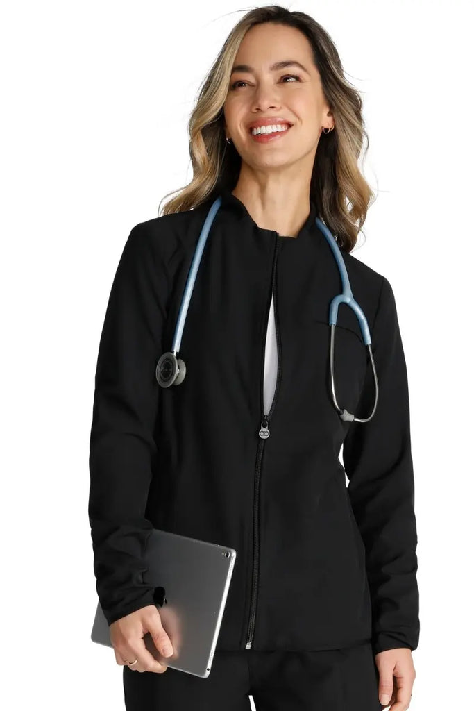 A young female nurse wearing an Allura Women's Zip-Up Jacket in Black size small featuring a funnel collar.