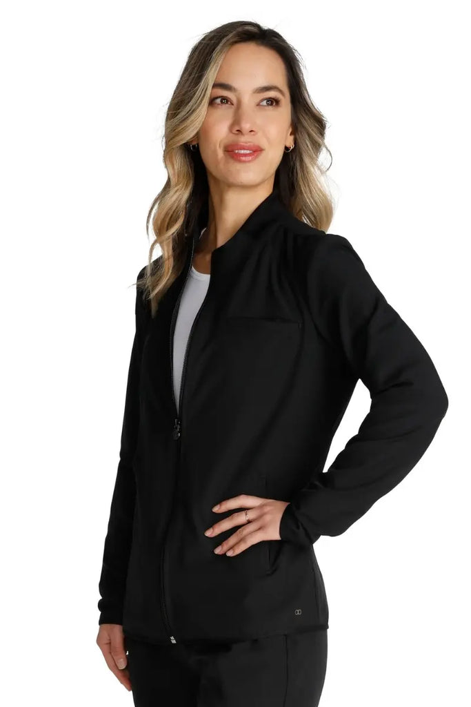 A young female CNA wearing an Allura Women's Zip Front Scrub Jacket in Black size XL featuring a contemporary fit.