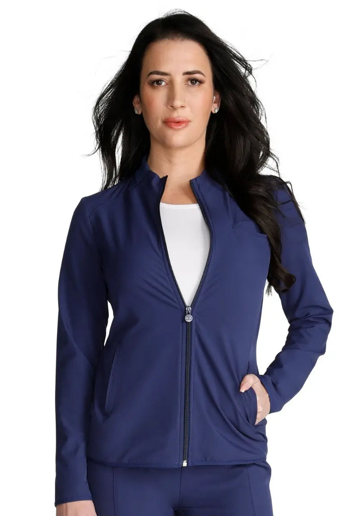 A young female Medical Assistant wearing an Allura Women's Zip-Up Jacket in Navy size small featuring a funnel collar.