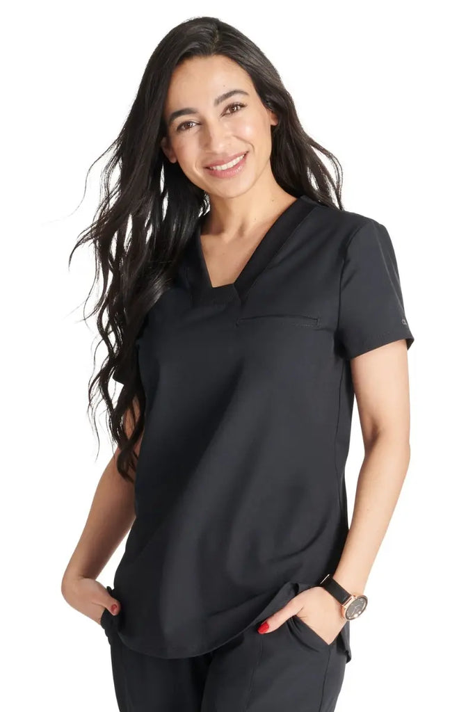 A young female Physical Therapist wearing an Allura Women's Mitered V-neck Scrub Top in Black size XS..