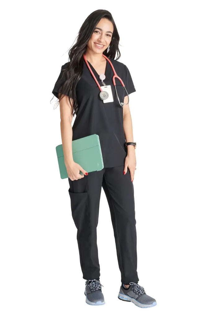 A full body shot of a young female Surgeon wearing an Allura Women's scrub uniform in Black size large.