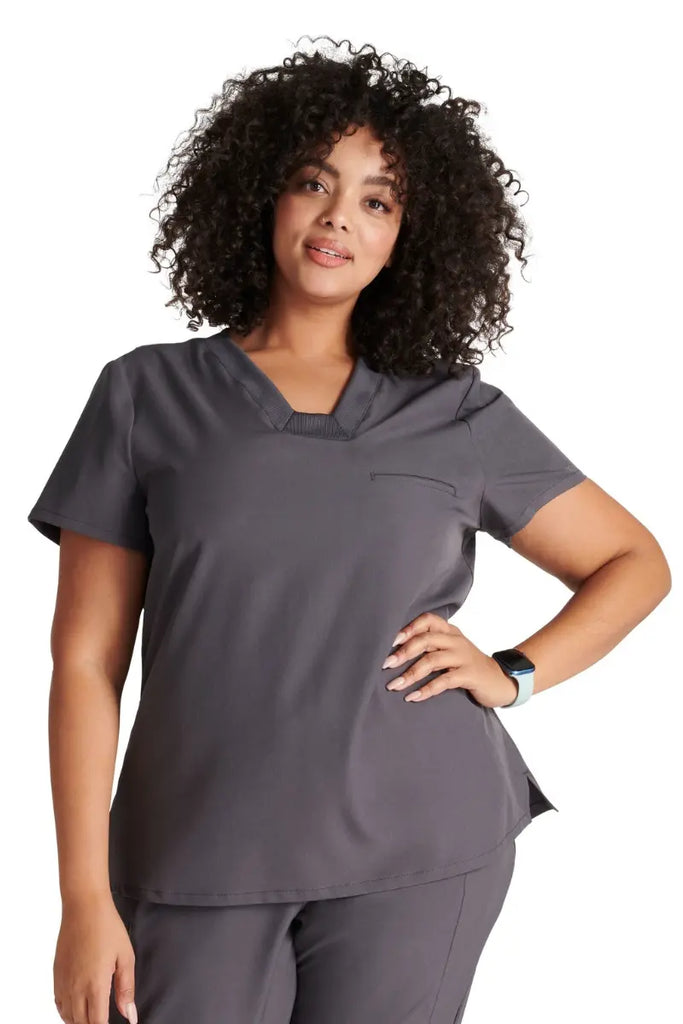 A young female Pharmacy Tech wearing an Allura Women's Mitered V-neck Scrub Top in Pewter Grey size 2XL.