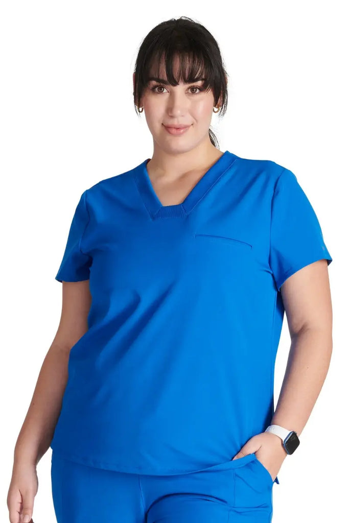 A young female Physical Therapist wearing an Allura Women's Mitered V-neck Scrub Top in Royal Blue size 2XL.