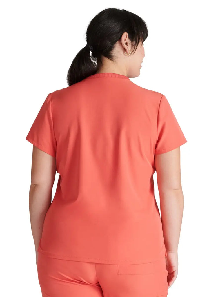 A young female LPN wearing an Allura Women's Stylized V-neck Scrub Top in Cayenne featuring a center back length of 25.5".