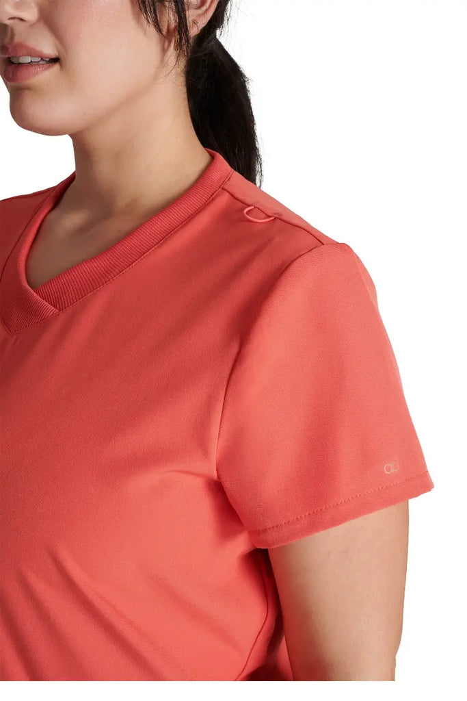 A close look at the left shoulder detail on the Allura Women's Stylized V-neck Scrub Top in Cayenne featuring a convenient badge ID bungee loop.