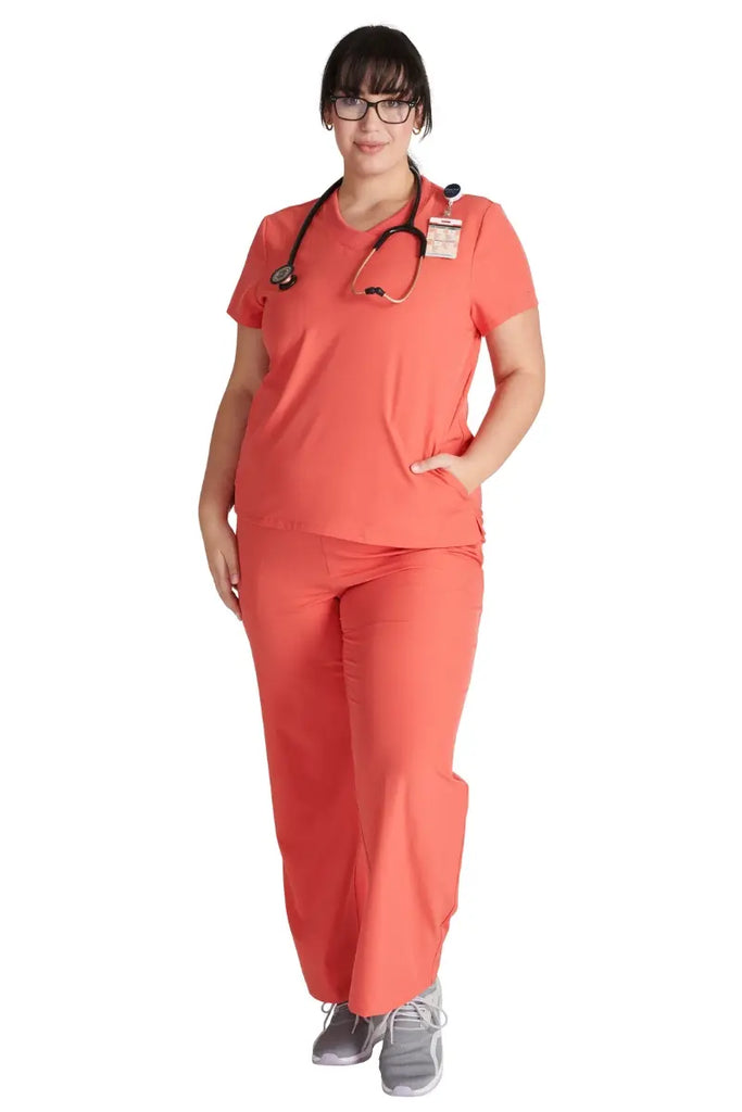 A full body shot of a young female Pediatrician wearing a Cayenne Allura scrub uniform.