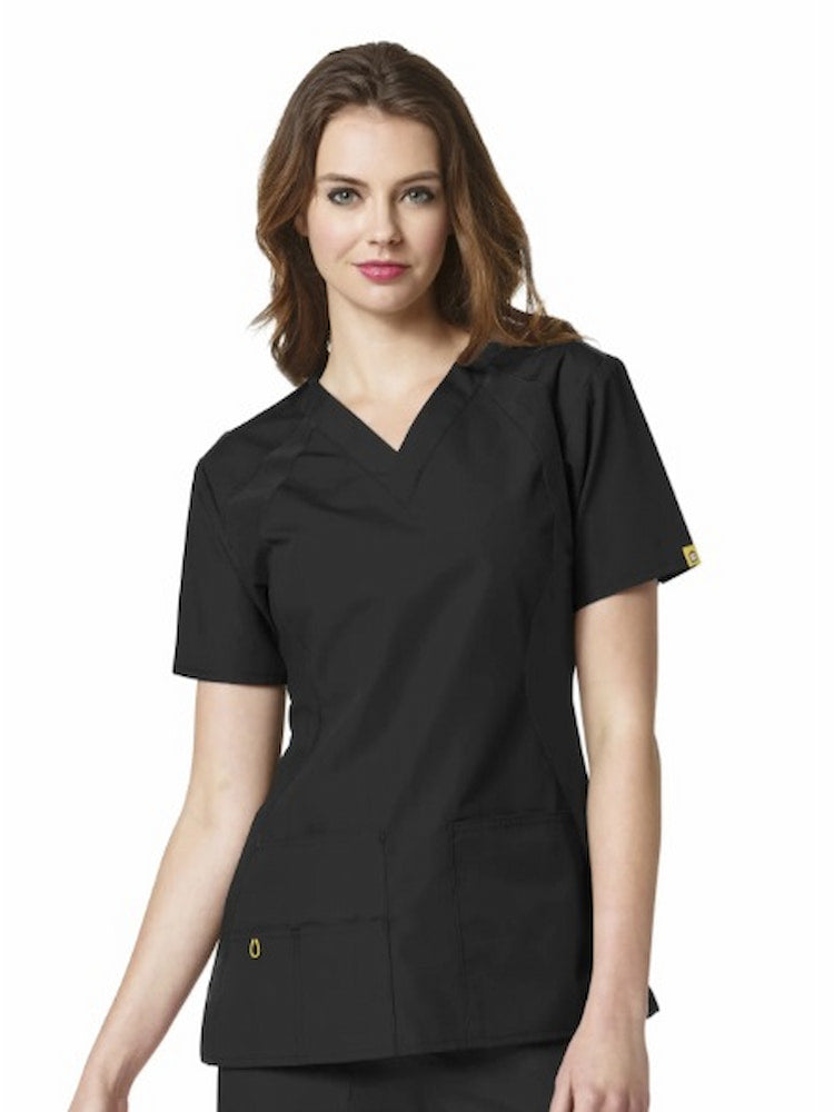A middle aged female Licensed Practical Nurse wearing a WonderWink Origins Women's Lima Knit Panel Scrub Top in Black size 3XL featuring vented sides for additional mobility throughout the day.