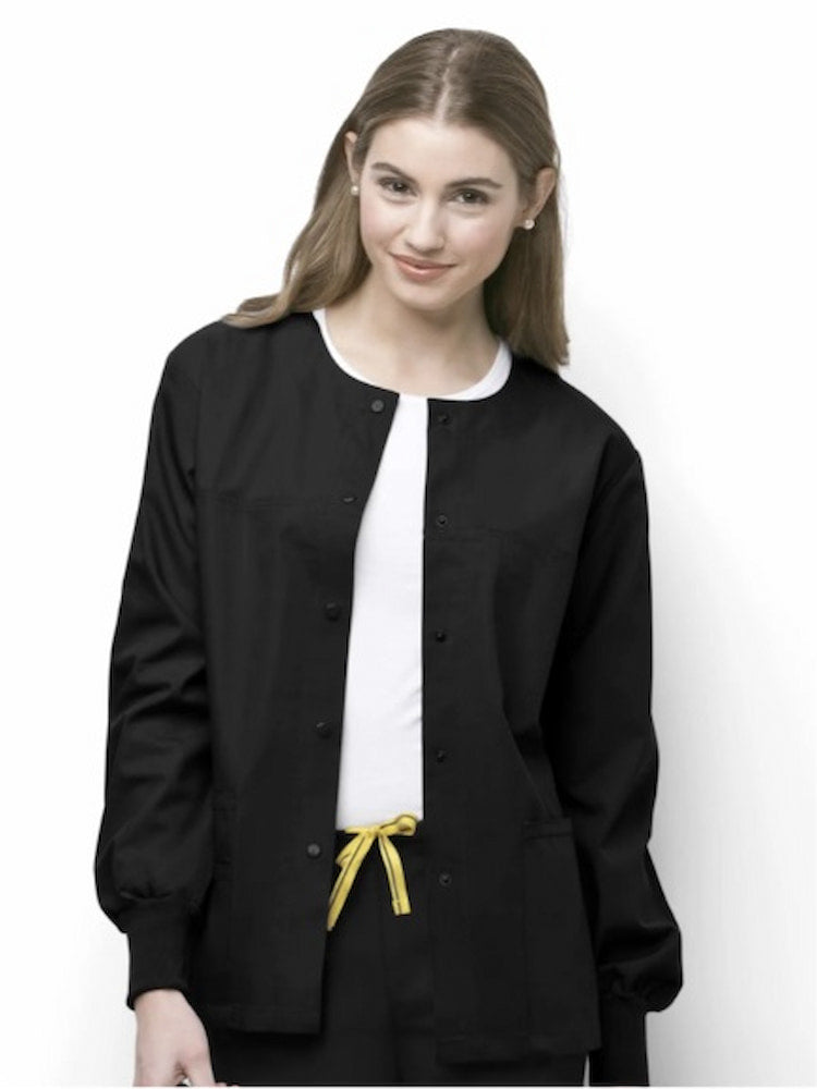 A young female Licensed Practical Nurse wearing a WonderWink Origins Delta Unisex Snap Front Scrub Jacket in Black size XL featuring two lower pockets including one WonderWink signature triple pocket with hidden mesh pocket, signature ID bungee loop, hidden utility loop & two invisible chest pockets.