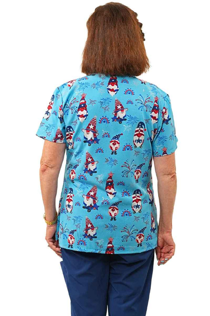 An image of a young female Nurse Practitioner wearing a Luv Scrubs by MedWorks Print Scrub Top in "Star Spangled Gnomes" in size XL featuring a center back length of 25".