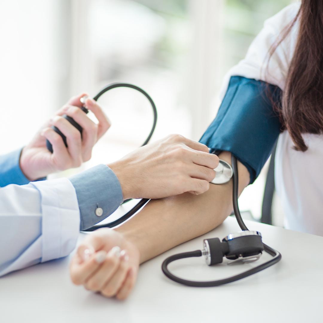 A young doctor using a blood pressure cuff to take a patients blood pressure.