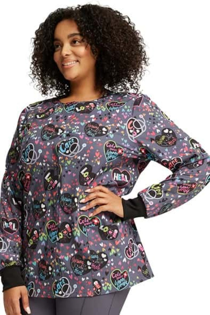 A young female CNA wearing a Cherokee Women's Print Snap Front Jacket in "Work of Heart" featuring a modern classic fit.