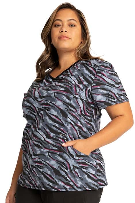A female Home Care Registered Nurse wearing a Cherokee Infinity Women's Mock Wrap Print Top in "Wild for Tie Dye" featuring a contrast rib-knit trimmed mock wrap neckline.