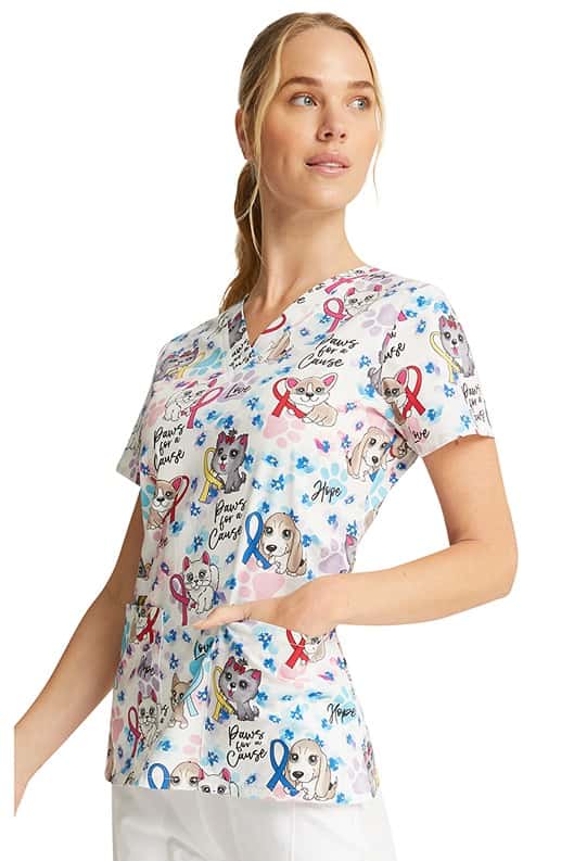 A young CNA wearing a Women's V-Neck Print Scrub Top from Cherokee in "Paws for a Cause" featuring 2 front patch pockets.