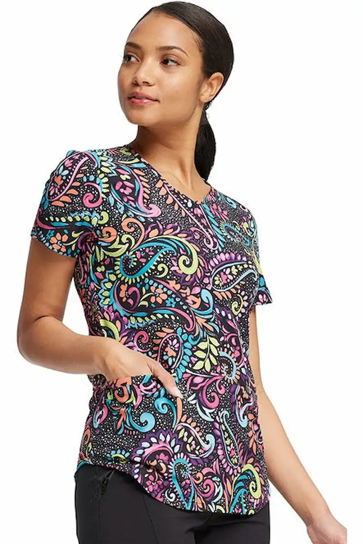 A young female CNA wearing a Cherokee Women's V-Neck Print Scrub Top in "Painted Paisley" featuring fun all over "Paisley" design is perfect for veterinary or pediatric settings!