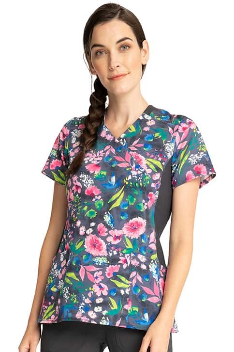 A young female RN wearing a Women's Knit Panel Print Top from Cherokee in "Watercolor Petals".