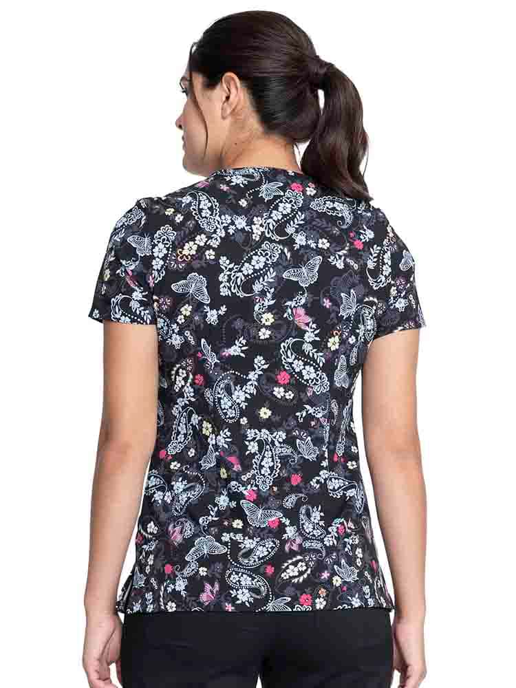 Young female healthcare worker wearing a Cherokee Women's V-Neck Print Top in "Flutter Blooms" featuring back darts to provide a flattering fit and shaping.