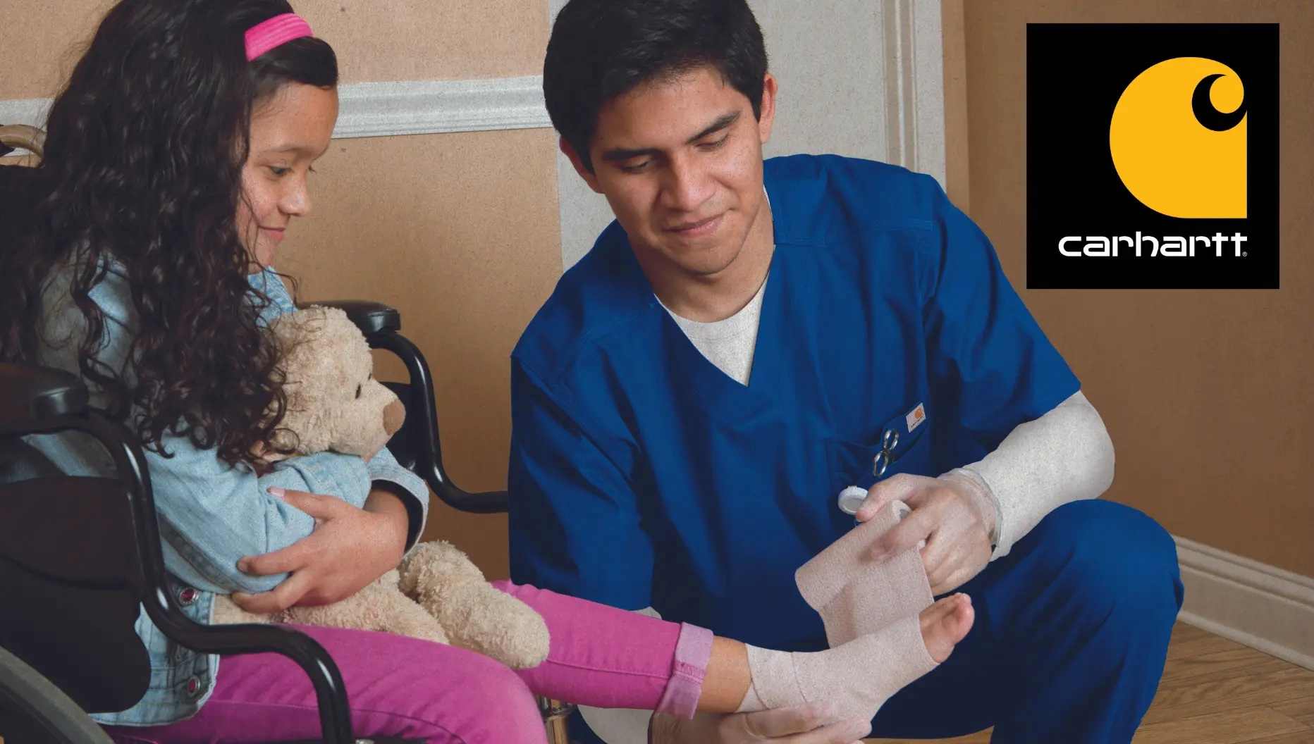 A male Pediatric Nurse wearing Royal Blue Carhartt scrubs while tending to a young patient. 