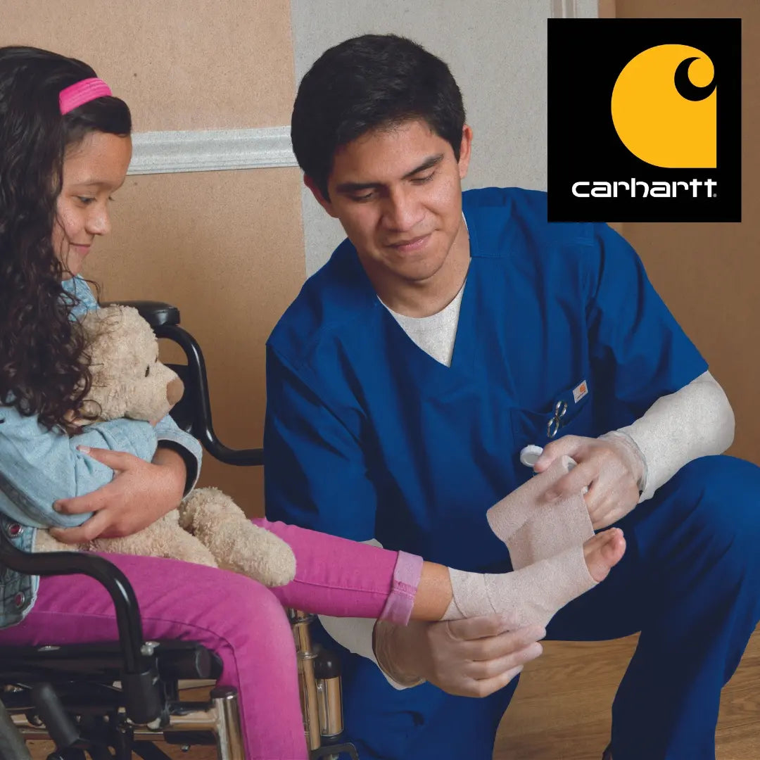 A young male Children's Nurse wearing Royal Blue Carhartt scrubs while tending to a young patient on a house call.