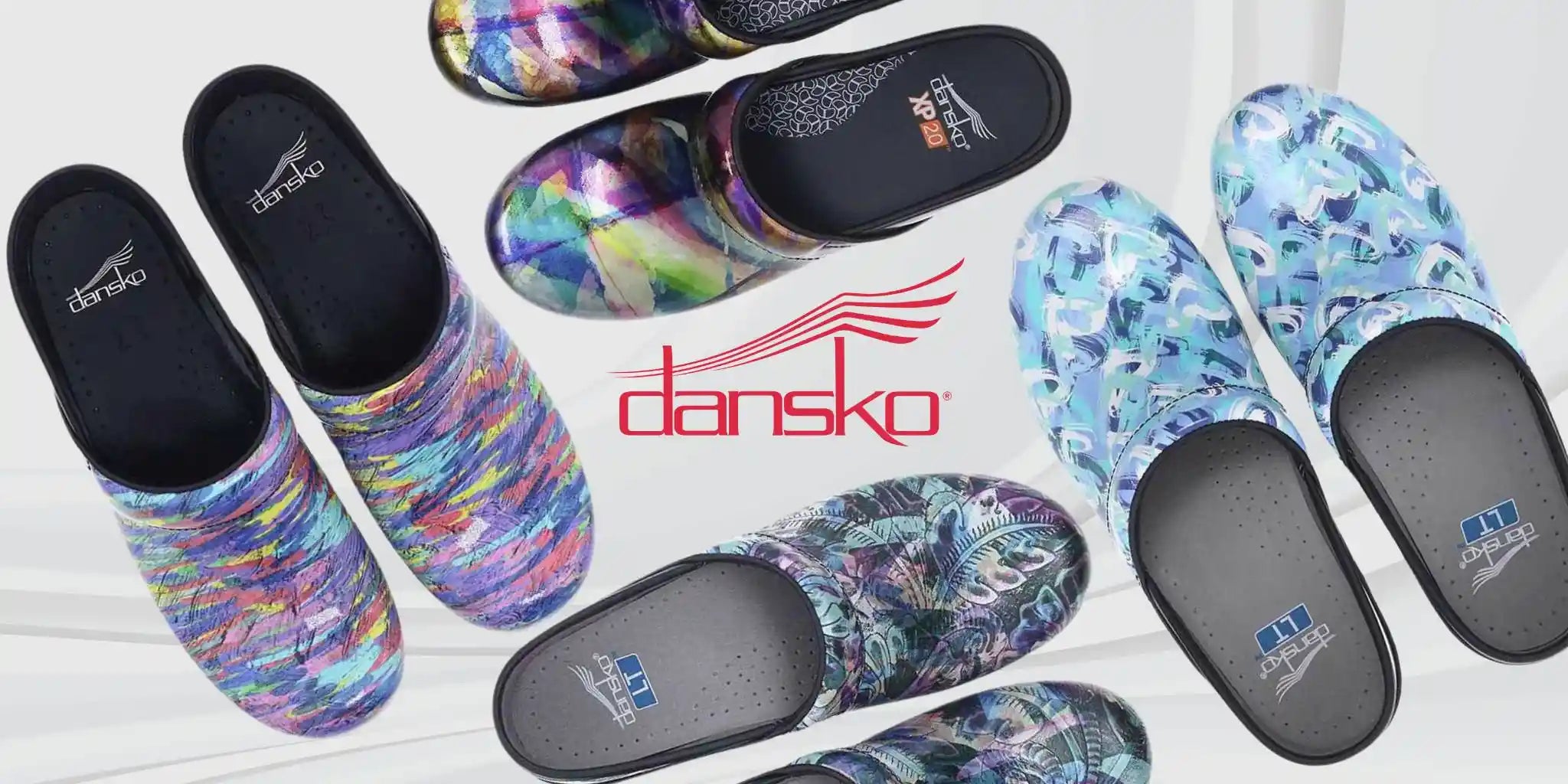 Four different pairs of Dansko Nurse Clogs in different styles laid across a  plain white background with the Dansko logo in the center.