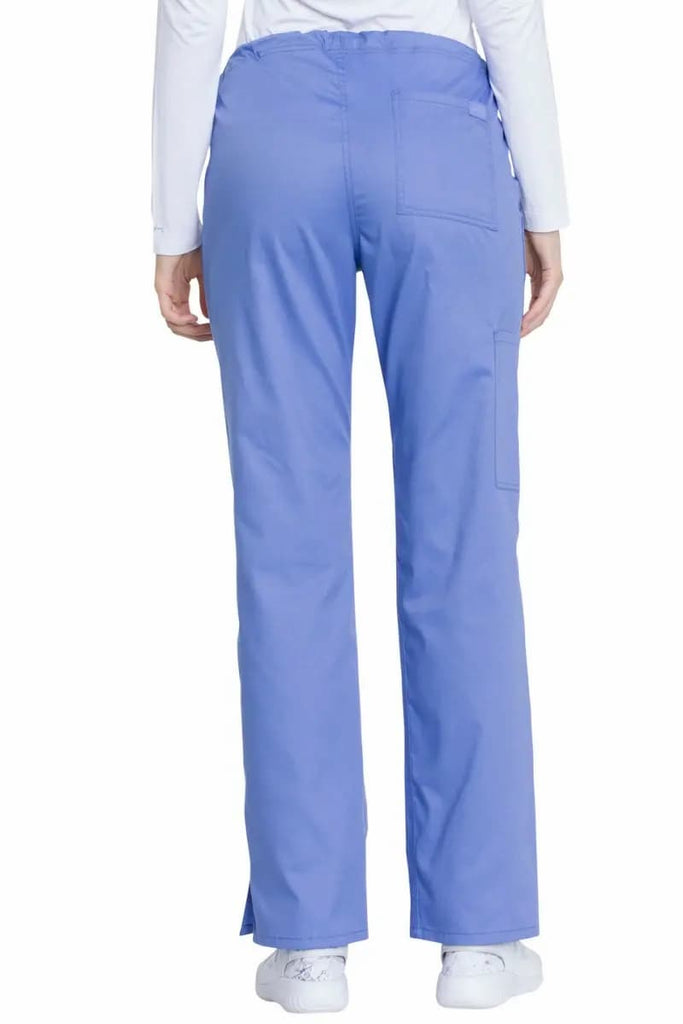 A young female Dental Hygienist wearing a pair of the Dickies Industrial Women's Drawstring Scrub Pants in Ceil Blue Medium Tall featuring a total of 4 pockets for additional storage space.