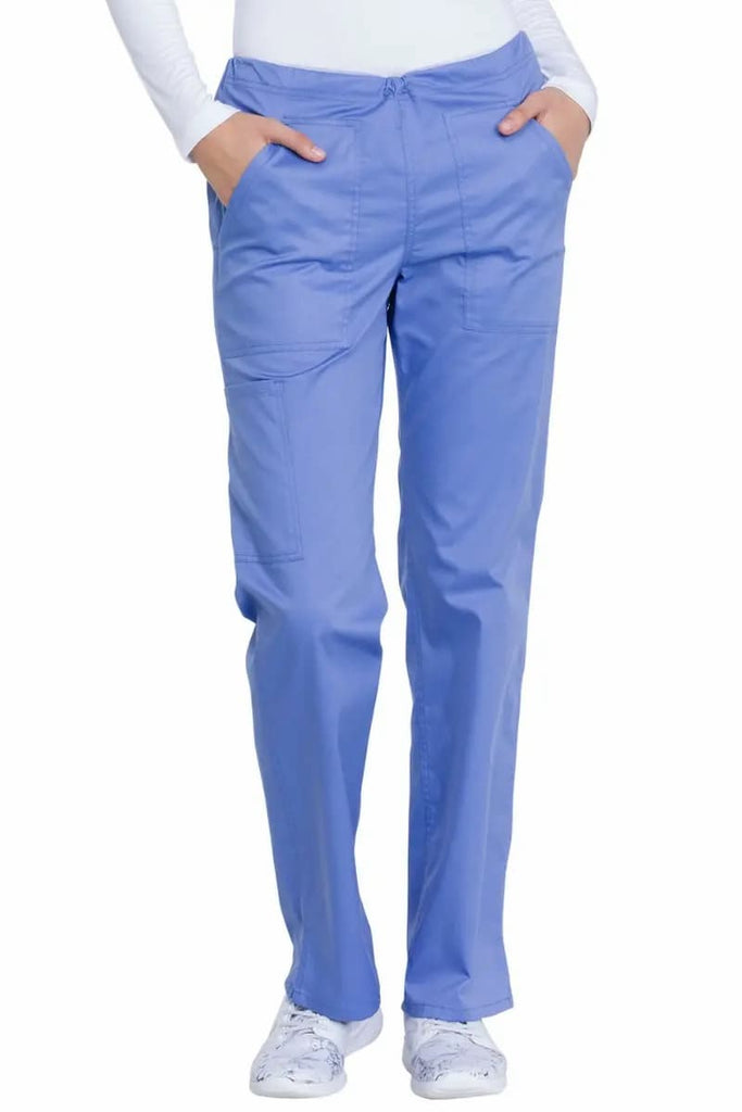 A young female Hospital Nurse wearing a pair of the Dickies Women's Drawstring Scrub Pants in Ceil Blue size XS Petite featuring a mid-rise comfort fit with the waistband sitting comfortably at the wearer's midsection for a secure and comfortable fit.