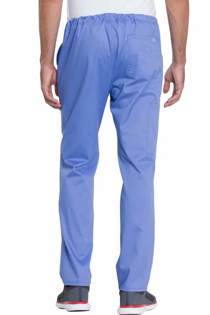 A young male Dental Assistant showcasing the back of the Dickies Industrial Unisex Mid-Rise  Scrub Pant in Ceil Blue featuring one back patch pocket on the wearer's right side.