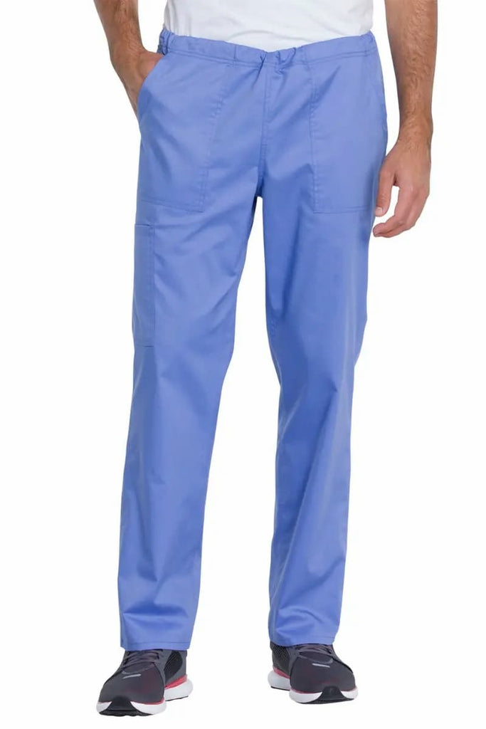 A young male Dental Hygienist wearing the Dickies Industrial Unisex Mid Rise Scrub Pant in Ceil Blue size Medium Tall featuring two front patch pockets for ample storage space.