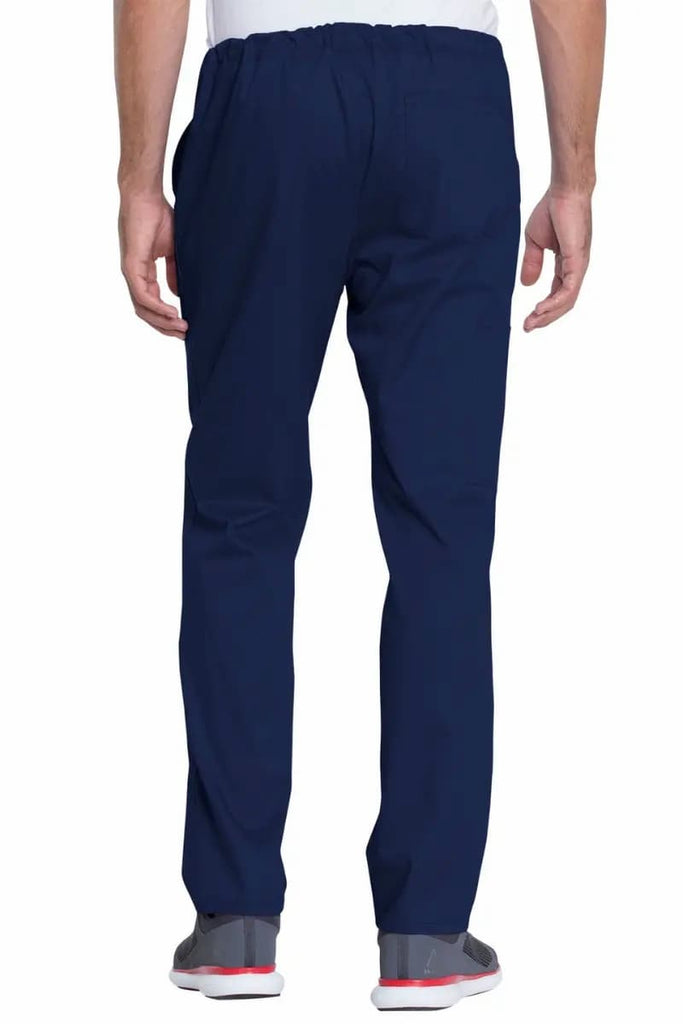 A male LPN wearing a pair of the Dickies Industrial Unisex Mid-Rise Scrub Pants in Navy Blue featuring a total of 4 pockets.