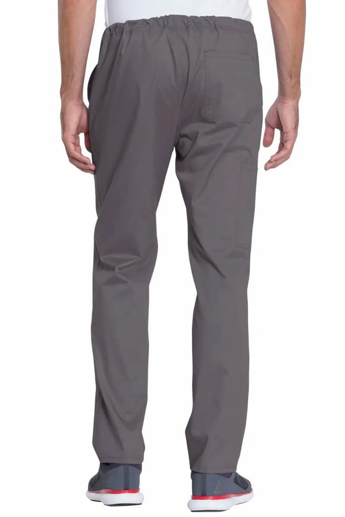A male Lab Tech wearing a Dickies Industrial Unisex Mid-Rise Scrub Pant in Pewter featuring a resilient 80% polyester / 20% cotton twill blend, that can handle industrial laundering.