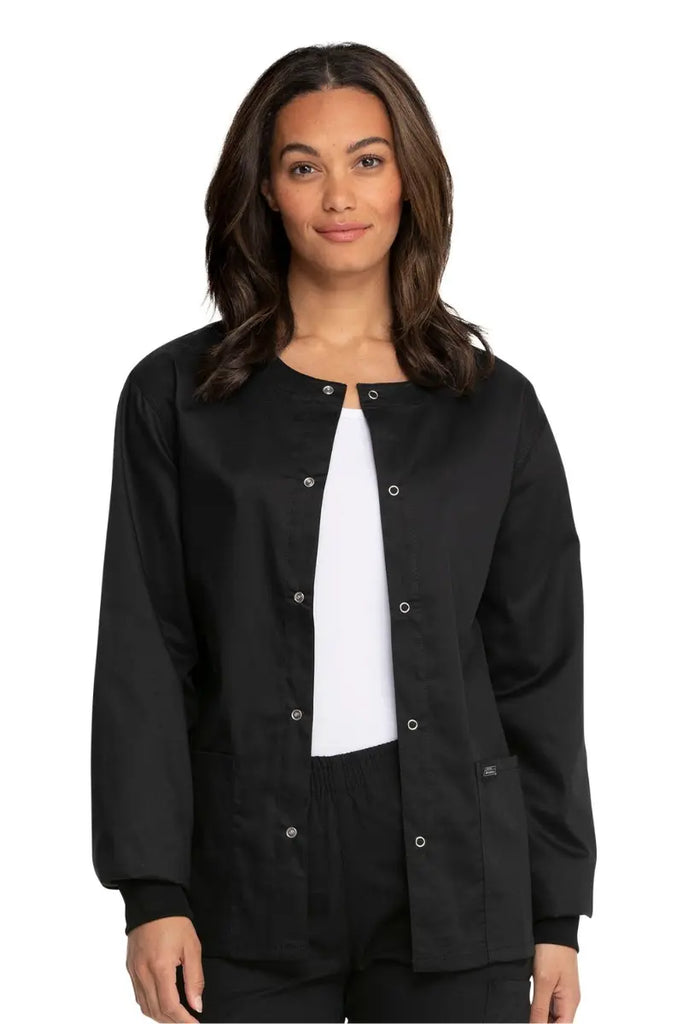 A young female Hospital Nurse wearing a Dickies Industrial Unisex Warm-Up Jacket in Black size XXS featuring a 5 metal button closure.
