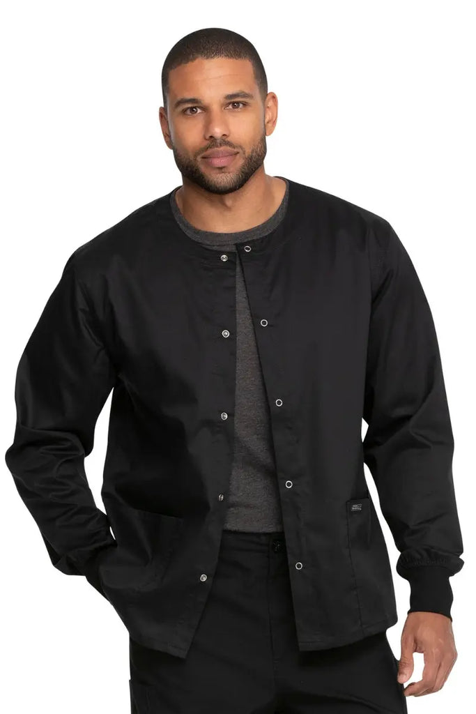 A young male Surgical Assistant wearing a Dickies Industrial Unisex Warm-Up Jacket in Black size 2XL featuring an easy care fabric made to withstand industrial laundering.