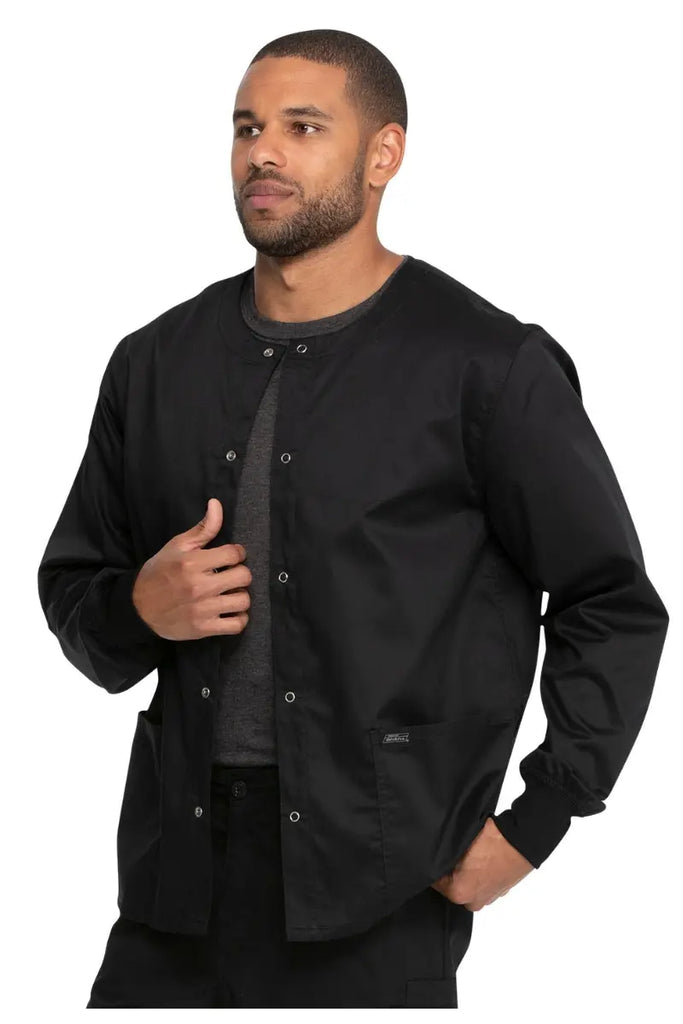 A young male Nurse Practitioner wearing a Dickies Industrial Unisex Warm-Up Scrub Jacket in Black featuring a rib knit hem for a snug and comfortable fit that keeps out drafts.