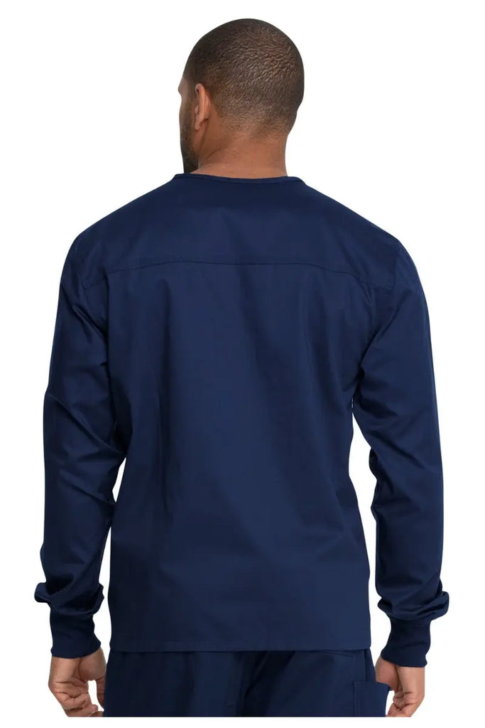 A young male Medical Assistant showcasing the back of the Dickies Unisex Warm-Up Scrub Jacket in Navy Blue featuring a flattering silhouette for all body types.