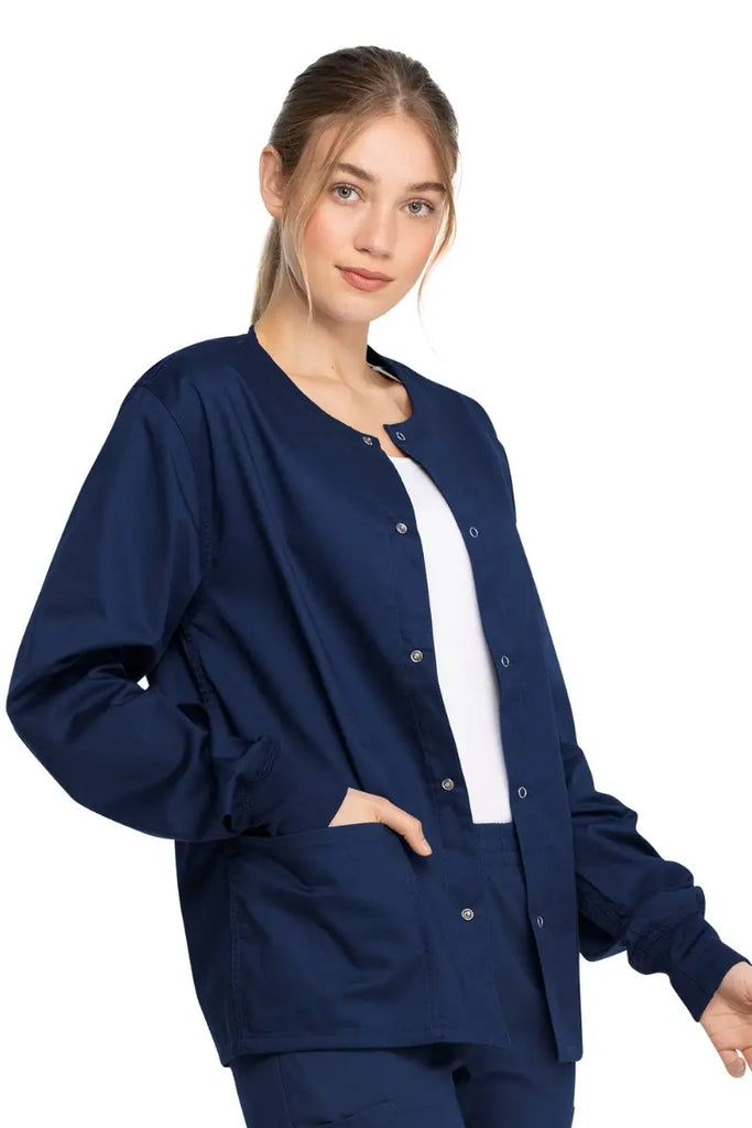 A young female RN wearing a Dickies Industrial Unisex Warm-Up Jacket in Navy Blue size Medium featuring rib knit cuffs for a snug and comfortable fit.