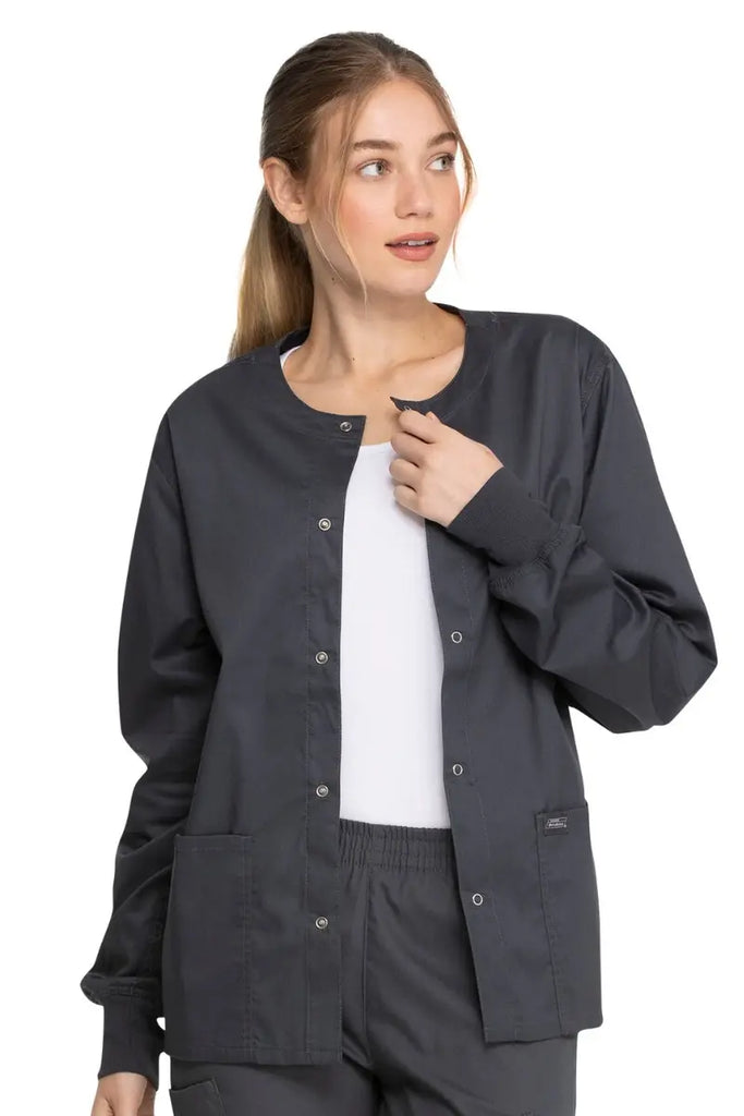 A young female Lab Tech wearing a Dickies Industrial Unisex Warm-Up Jacket in Pewter size Small featuring a 5 metal button closure.