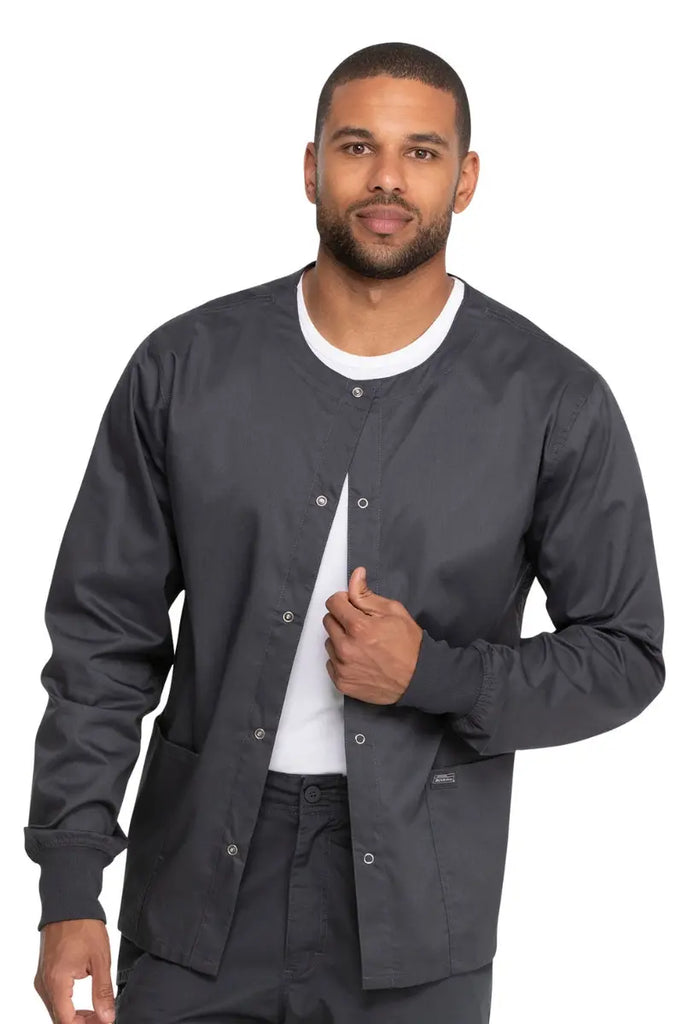 A young male Medical technologist wearing a Dickies Industrial Unisex Warm-Up Scrub Jacket in Pewter size 4XL featuring an easy care fabric made to withstand industrial laundering.