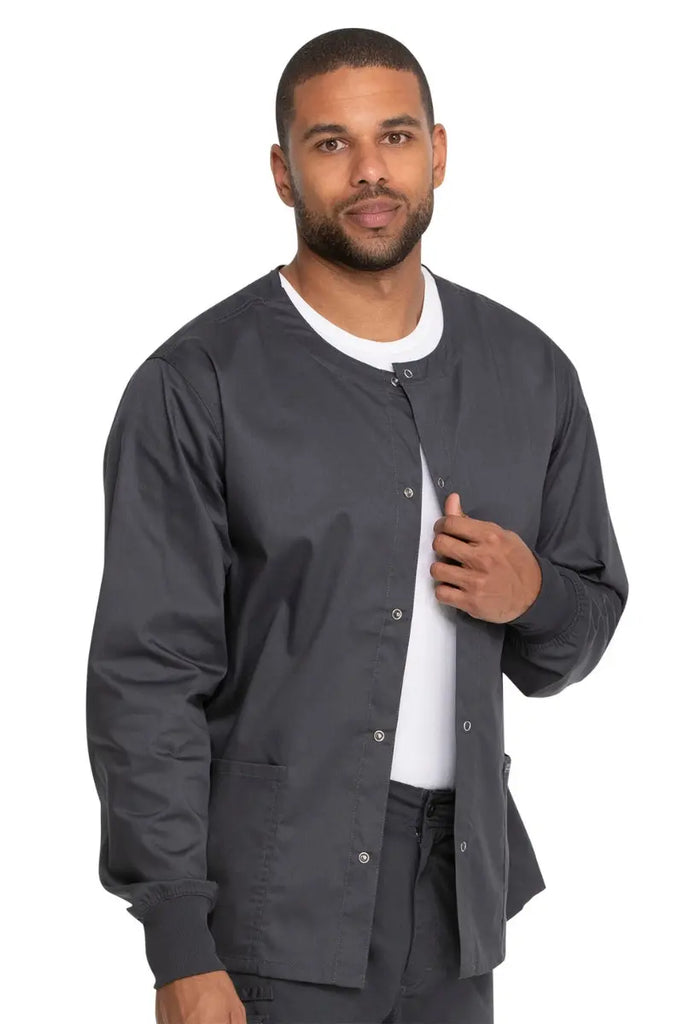 A young male Radiologic Technologist wearing a Dickies Industrial Unisex Warm-Up Scrub Jacket in Pewter featuring two large front patch pockets.