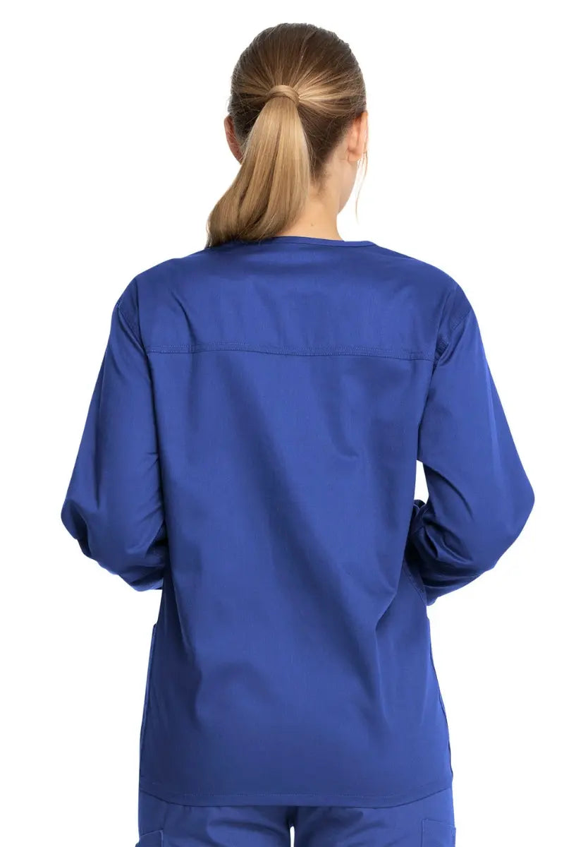 A young female PTA showcasing the back of the Dickies Industrial Unisex Warm-Up Scrub Jacket in Royal Blue featuring a center back length of 29".