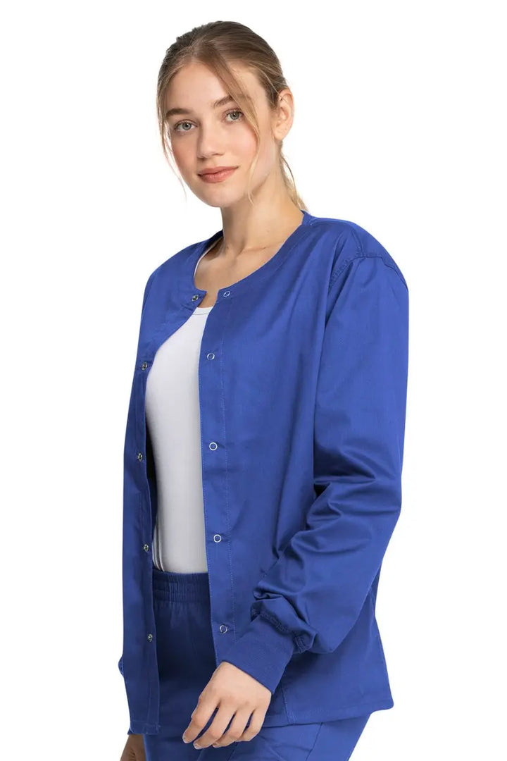 A young female Geriatric Medical Assistant wearing a Dickies Industrial Unisex Warm-Up Scrub Jacket in Royal Blue size XL featuring a durable 80% polyester / 20% cotton stretch twill that can withstand daily wear and washing demands.