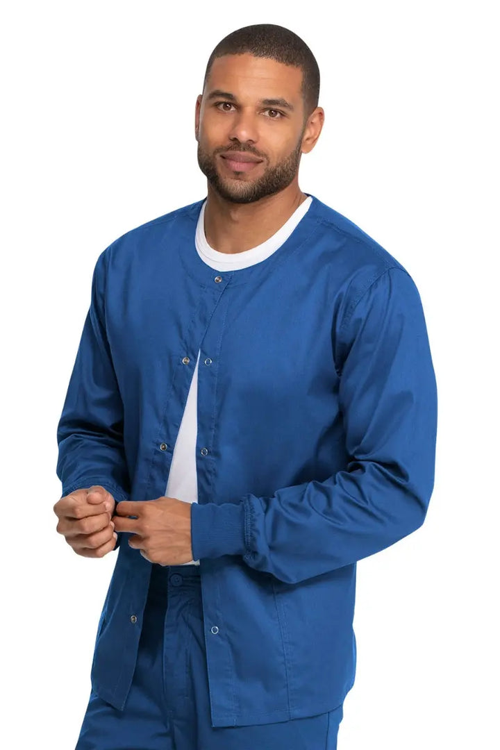 A young male Physical Therapist wearing a Dickies Industrial Unisex Warm-Up Scrub Jacket in Royal Blue featuring a rib knit hem for a snug and comfortable fit that keeps out drafts.