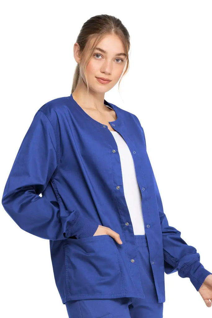A young female Pediatric Medical Assistant wearing a Dickies Industrial Unisex Warm-Up Jacket in Royal Blue size Medium featuring rib knit cuffs for a snug and comfortable fit.