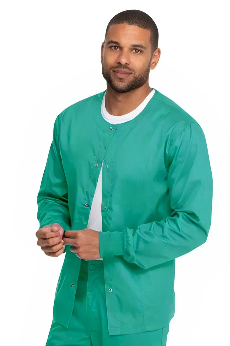 A young male Circulating Nurse wearing a Dickies Industrial Unisex Warm-Up Scrub Jacket in Surgical Green featuring a rib knit hem for a snug and comfortable fit that keeps out drafts.