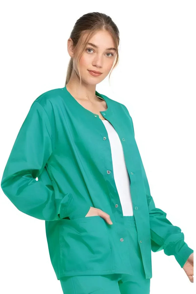 A young female Surgeon wearing a Dickies Industrial Unisex Warm-Up Jacket in Surgical Green size Large featuring rib knit cuffs for a snug and comfortable fit.