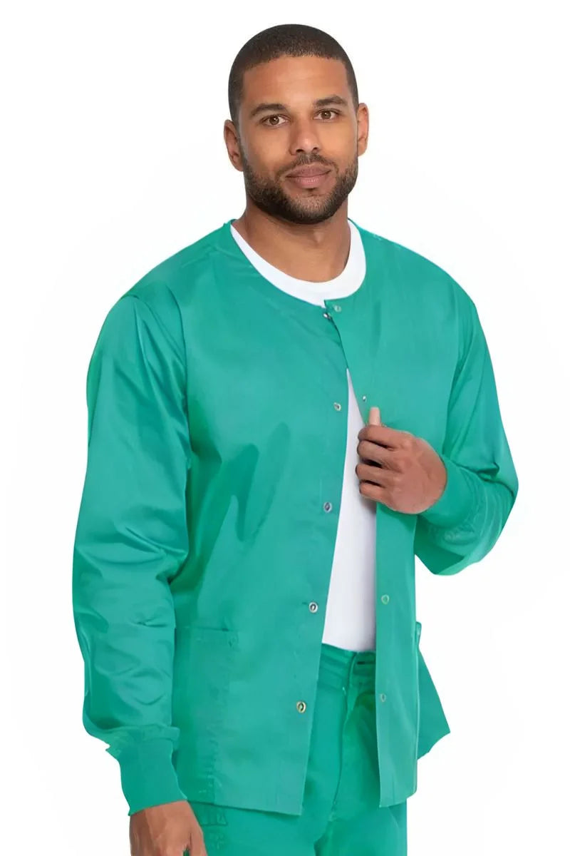 A young male Scrub Suit wearing a Dickies Industrial Unisex Warm-Up Scrub Jacket in Surgical Green featuring two large front patch pockets.