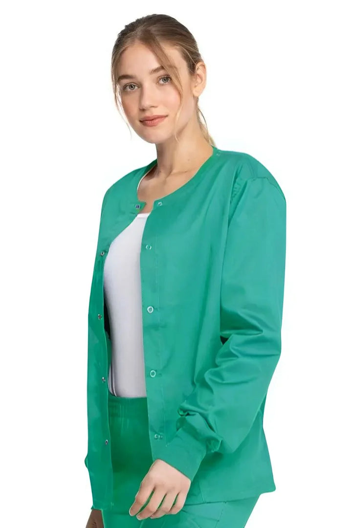 A young female Anesthesiologist wearing a Dickies Industrial Unisex Warm-Up Scrub Jacket in Surgical Green size Small featuring a durable 80% polyester / 20% cotton stretch twill that can withstand daily wear and washing demands.