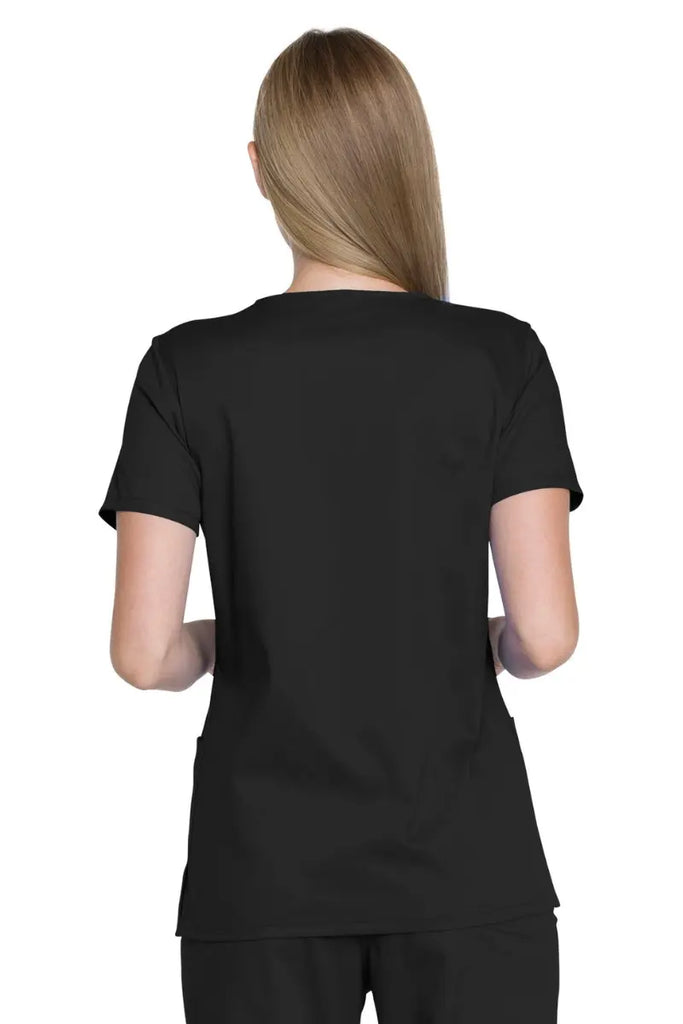 A young female Surgical Specialist showcasing the back of the Dickies Industrial Women's V-neck Scrub Top in Black size Medium featuring a center back length of 26".